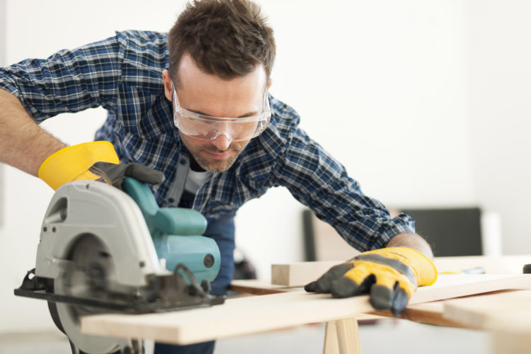 Hard working carpenter cutting wooden plank